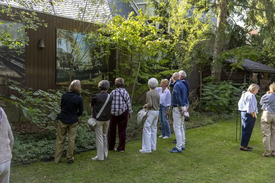 Bezoekers bekijken een groot schilderij aan een tuinhuis